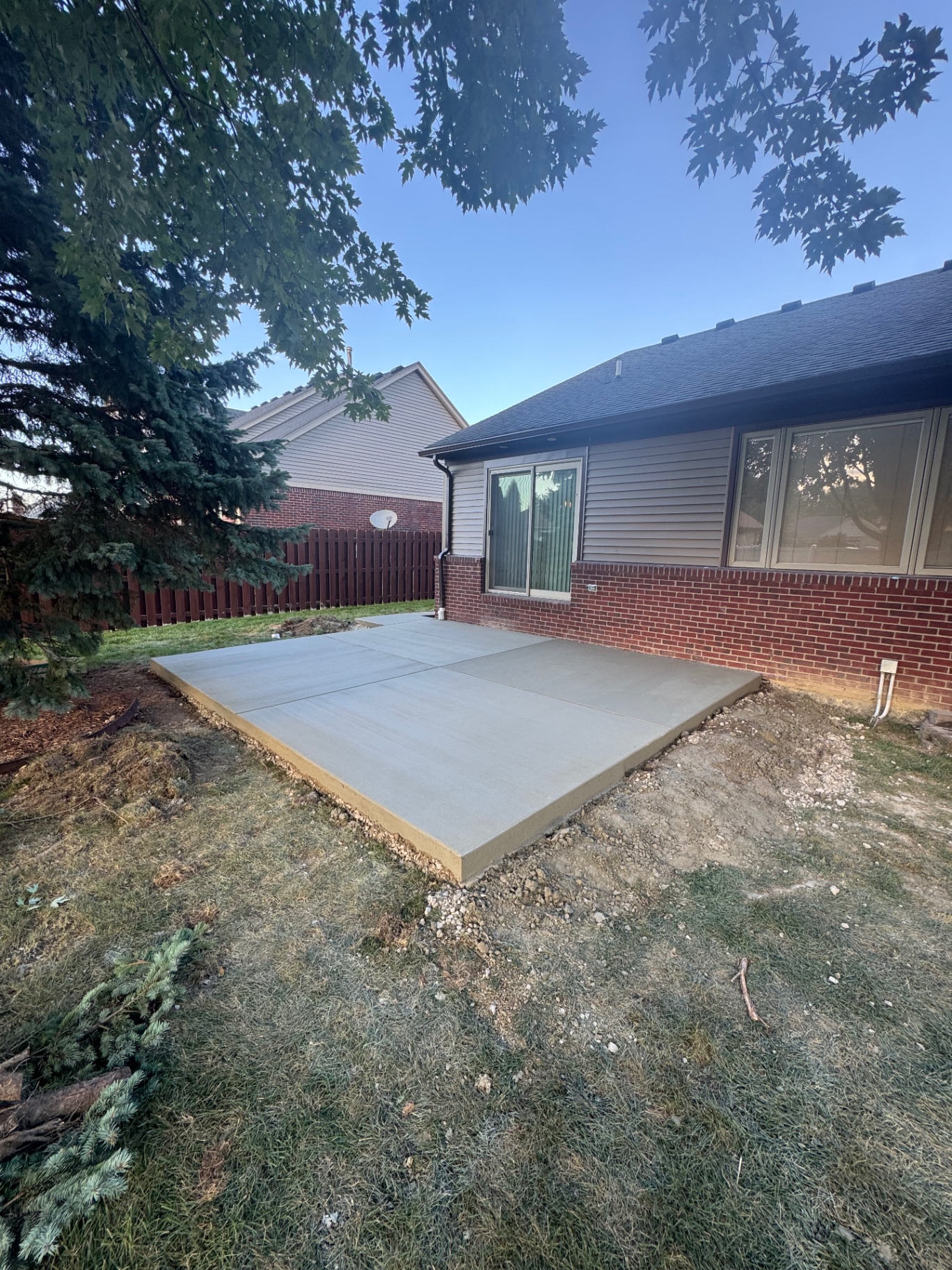 Freshly finished broom-finish concrete patio behind a brick and siding home