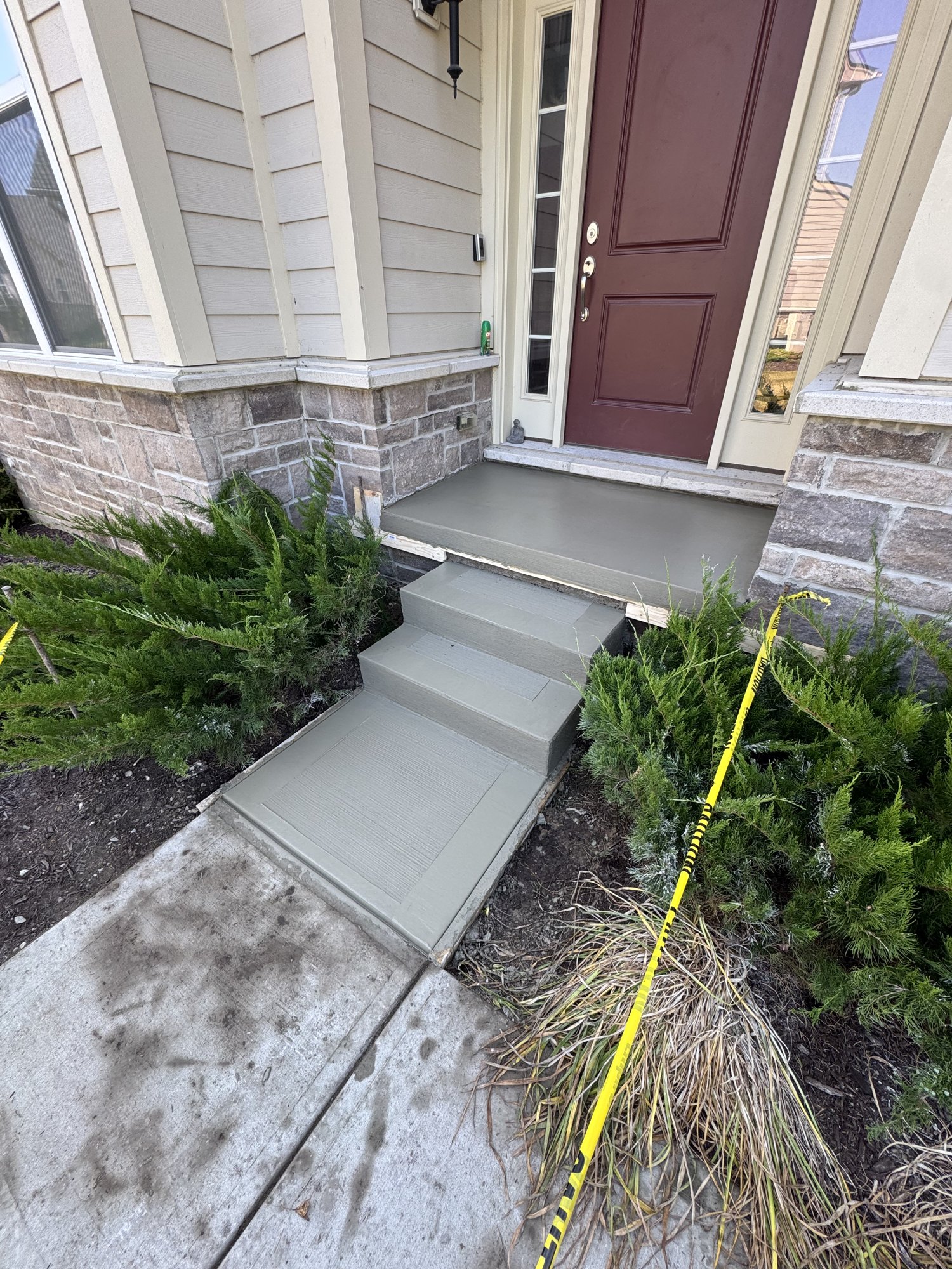 New concrete front entry steps and landing at a stone-faced home