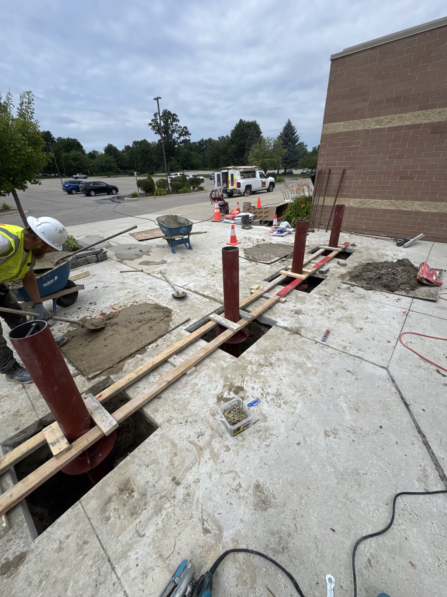 Concrete being placed around braced safety bollard posts during a commercial bollard installation