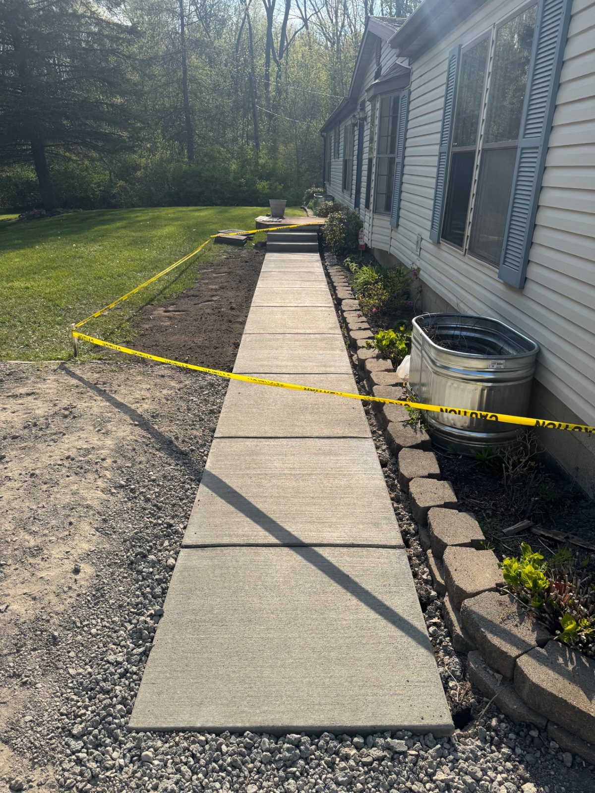 Freshly broomed concrete walkway running to the front steps of a home with forms removed and edges waiting on backfill