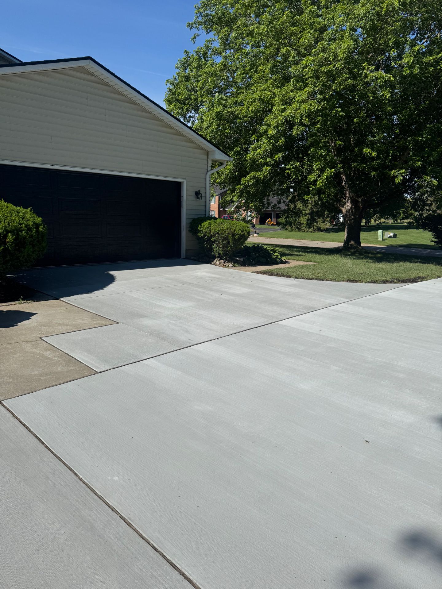Completed broom-finished concrete driveway replacement with clean joint layout at a Southeast Michigan home