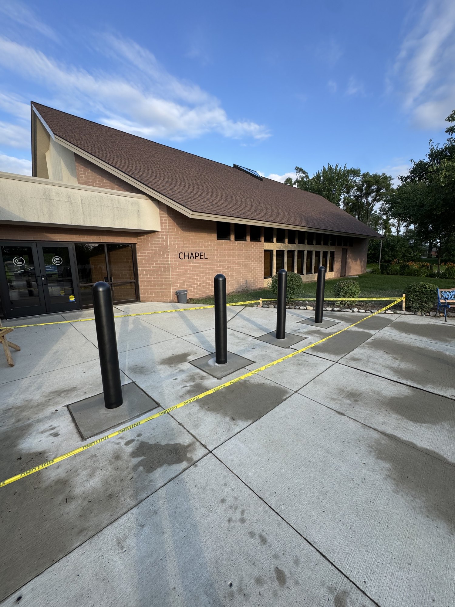 Four finished black safety bollards set in new concrete at a building entrance