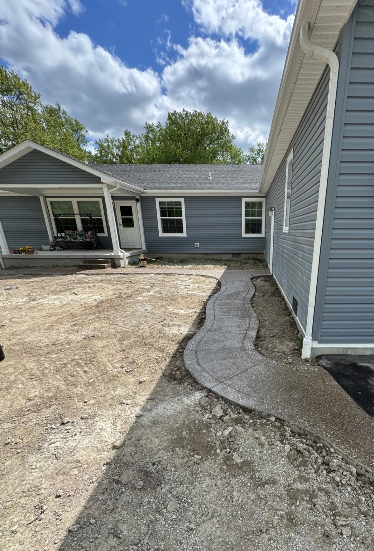 Winding exposed aggregate walkway beside a garage leading to a covered porch