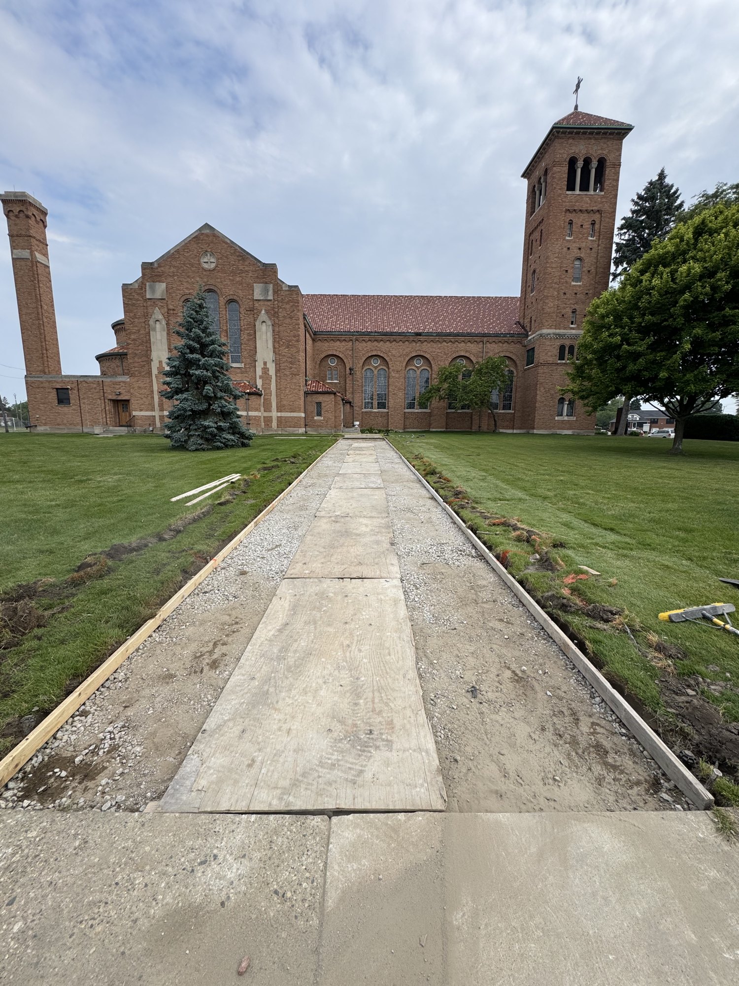 Formed walkway with compacted stone base prepared ahead of a concrete entry walk replacement at a church