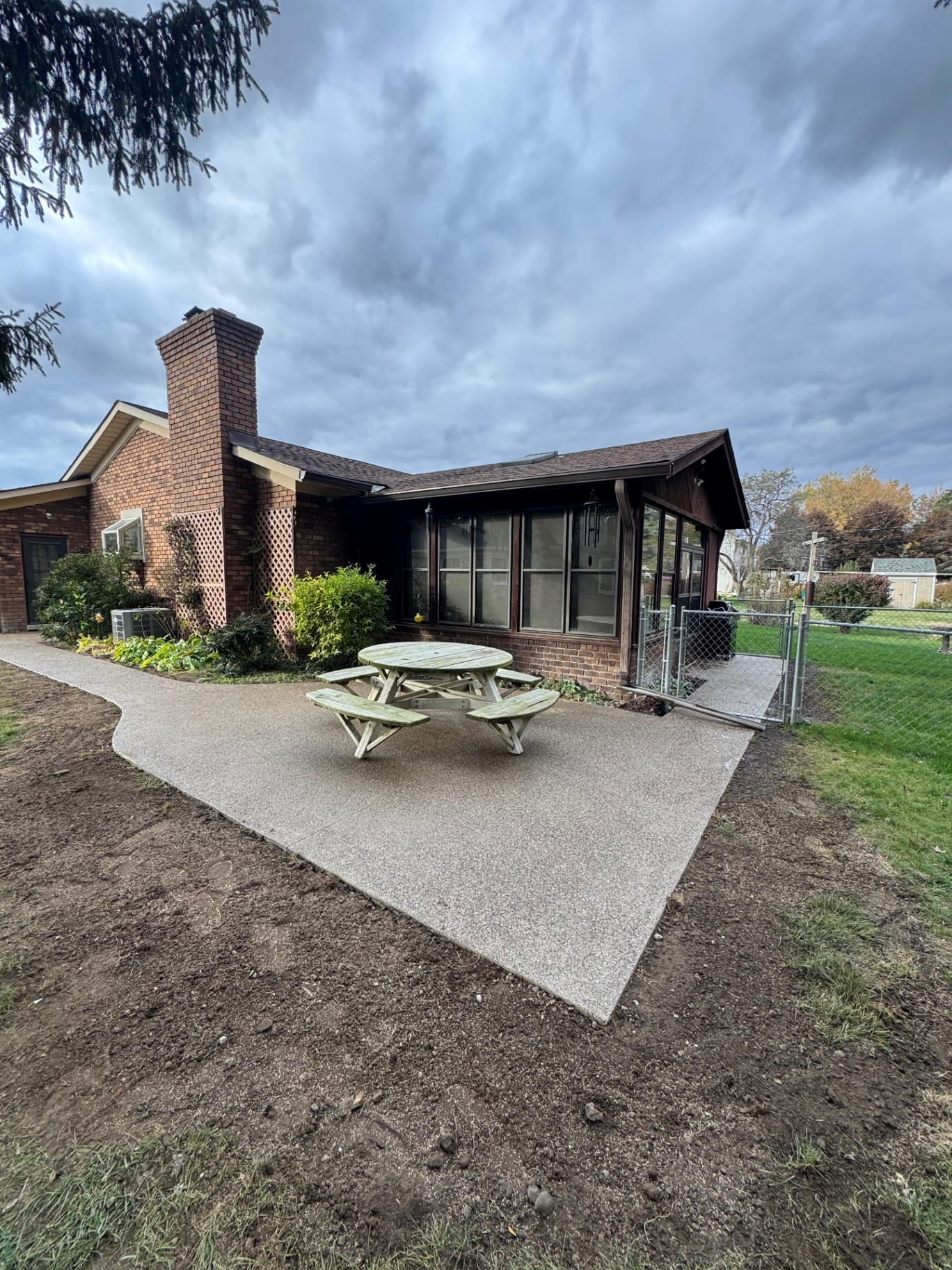 Exposed aggregate concrete patio and connecting walkway behind a brick ranch home in Southeast Michigan